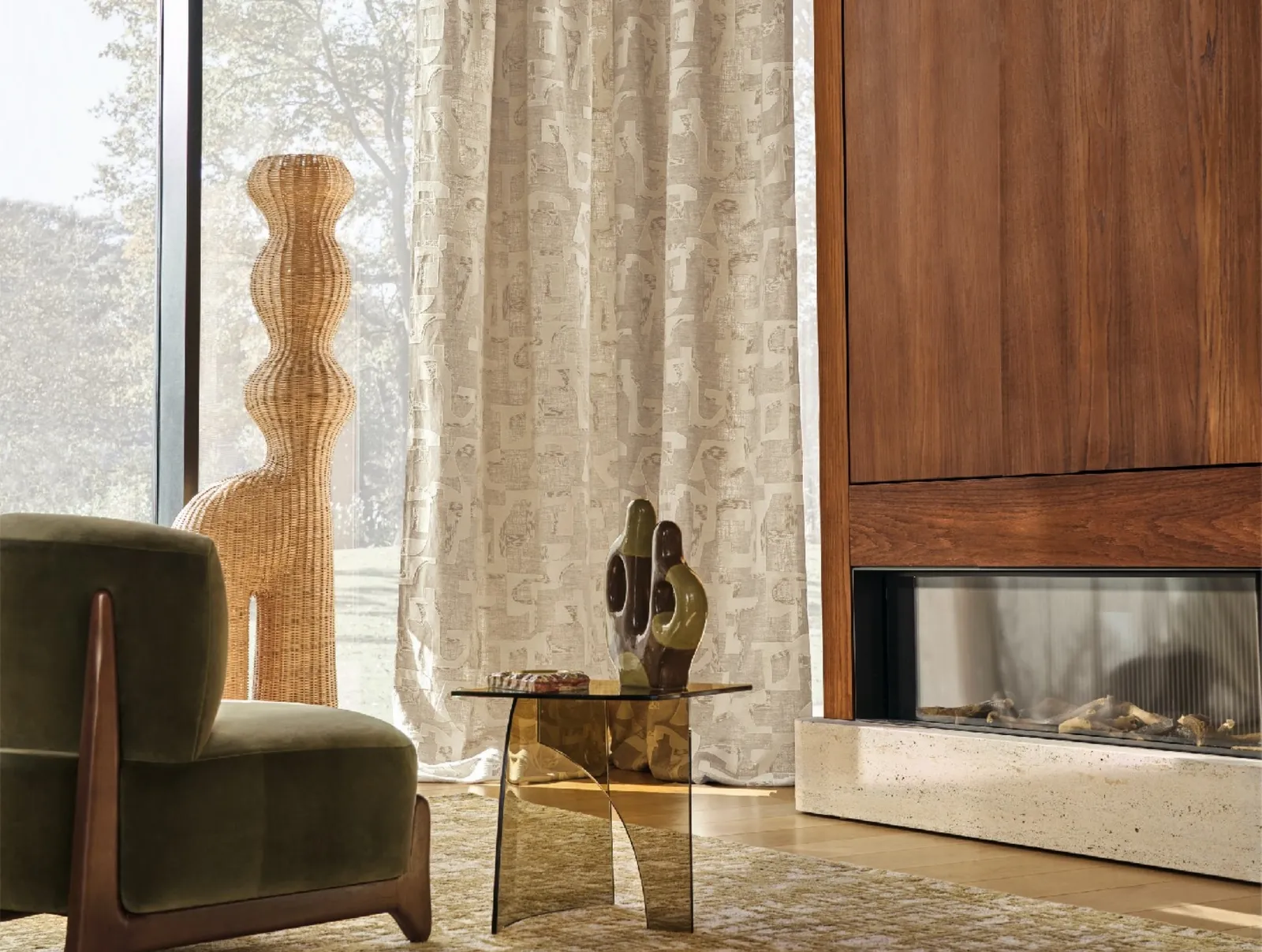 Sheer curtain behind a green armchair and woven floor lamp by a fireplace