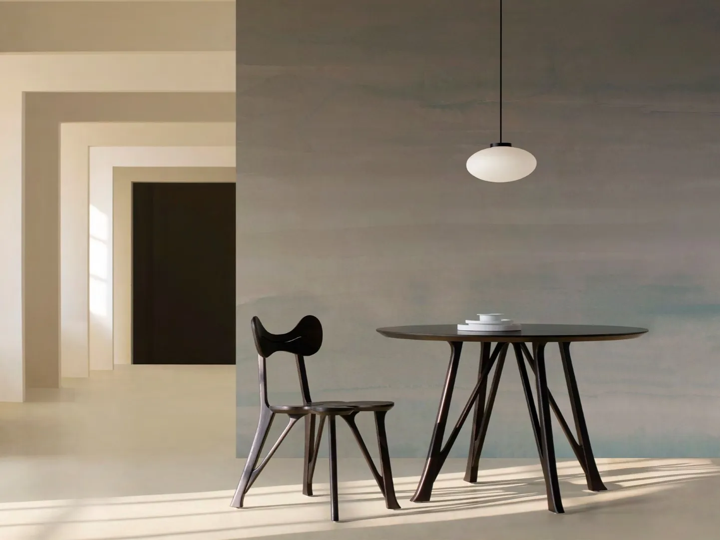 Round dining table and chairs before a misty grey mural