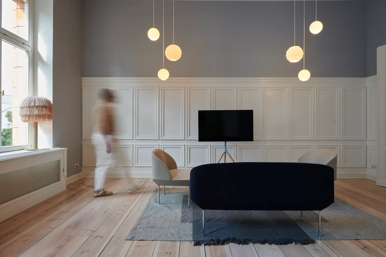 Panelled living room with globe pendant lights and a figure walking past