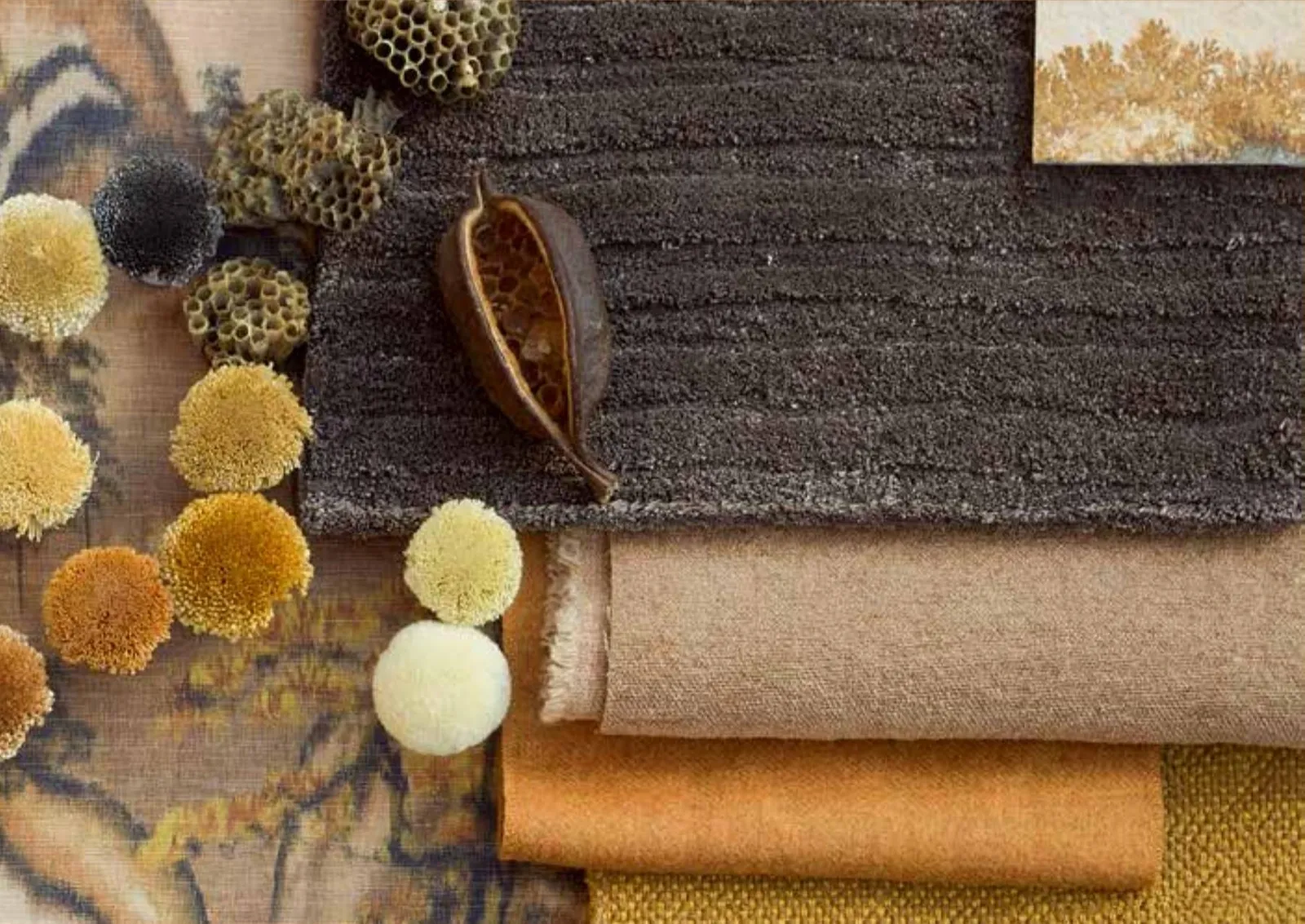 Earth-toned fabric swatches with pompom trims and dried seed pods